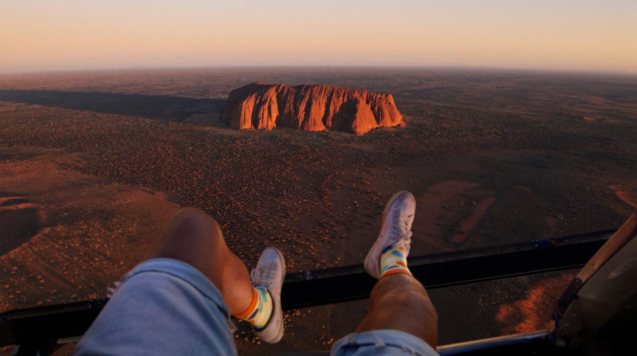 Man riding in a helicopter with his legs hanging out the side